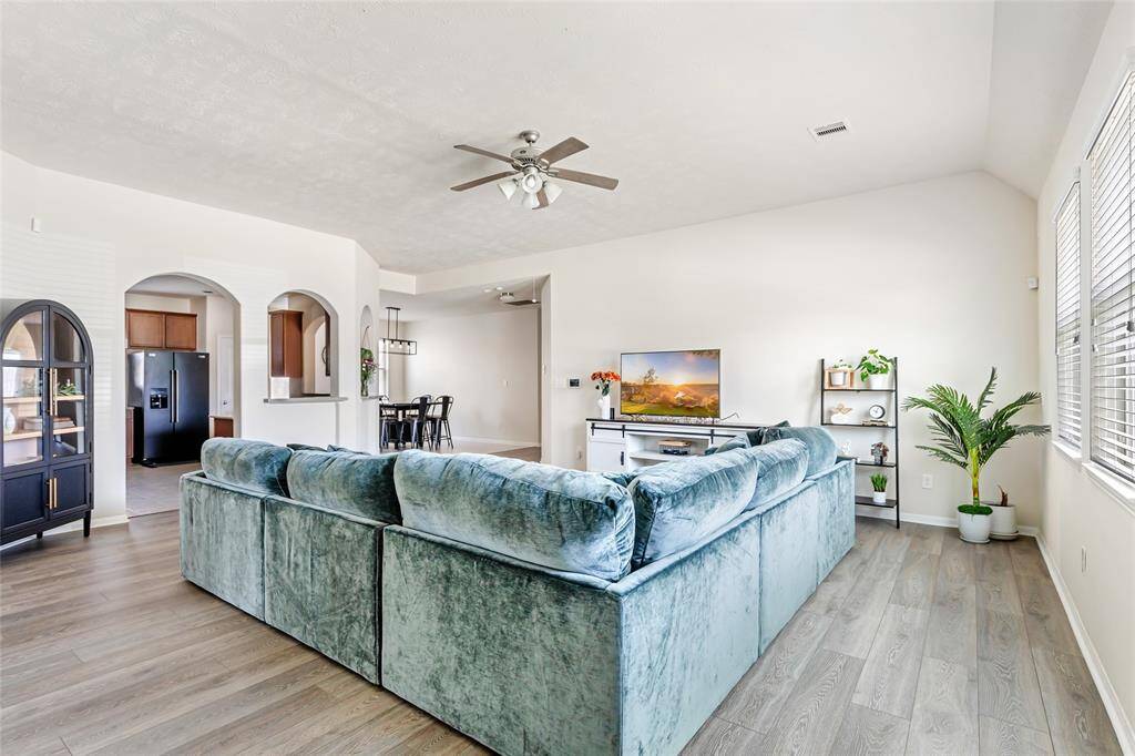 Bright, open-concept living area with modern finishes, featuring large windows. The space connects seamlessly to the kitchen and dining area, ideal for entertaining. Stylish decor and natural light enhance the inviting atmosphere.