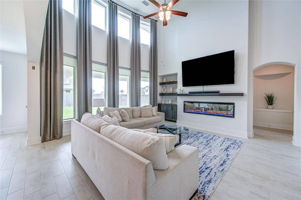 This den features a stunning color-changing fireplace and soaring windows with remote-controlled shades and drapes for ultimate comfort and style.