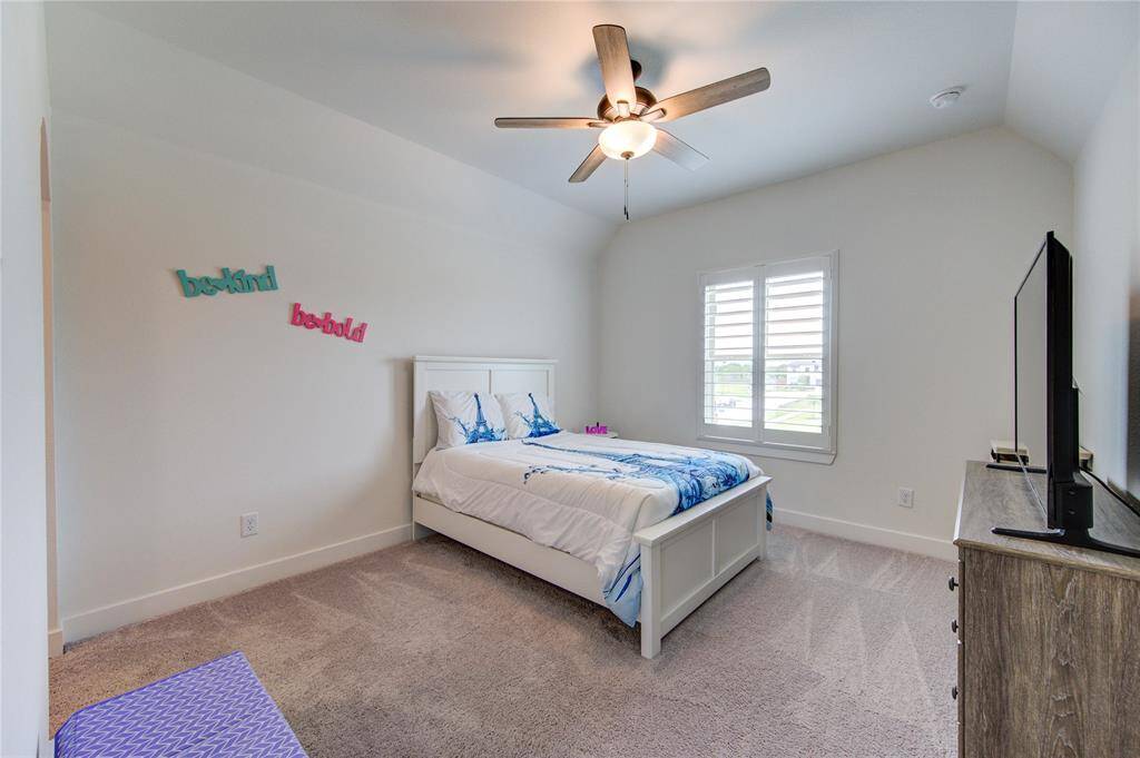 Cozy and inviting, this bedroom features plush carpeting, a ceiling fan, and ample natural light through stylish shutters. Perfect for restful nights.