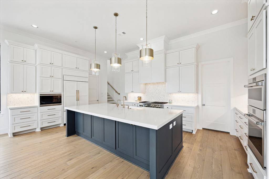 The kitchen boasts a sleek Sub-Zero paneled refrigerator and a Wolf microwave, combining luxury with modern convenience.