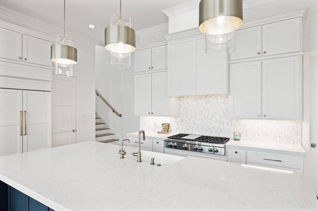 The kitchen features a Wolf 6-burner gas range with grill, complemented by a striking marble backsplash. Easily prepare your favorite beverage with a separate instant hot and cold water faucet.