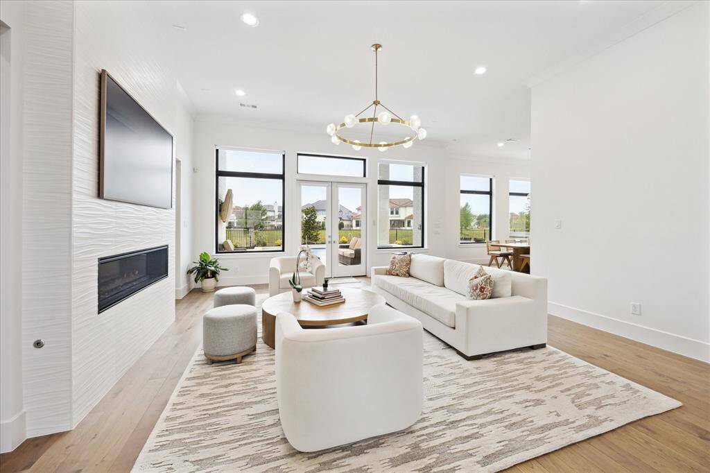 Floor to ceiling windows and French doors offer a serene view overlooking the sparkling pool and lake, creating a seamless indoor-outdoor ambiance.