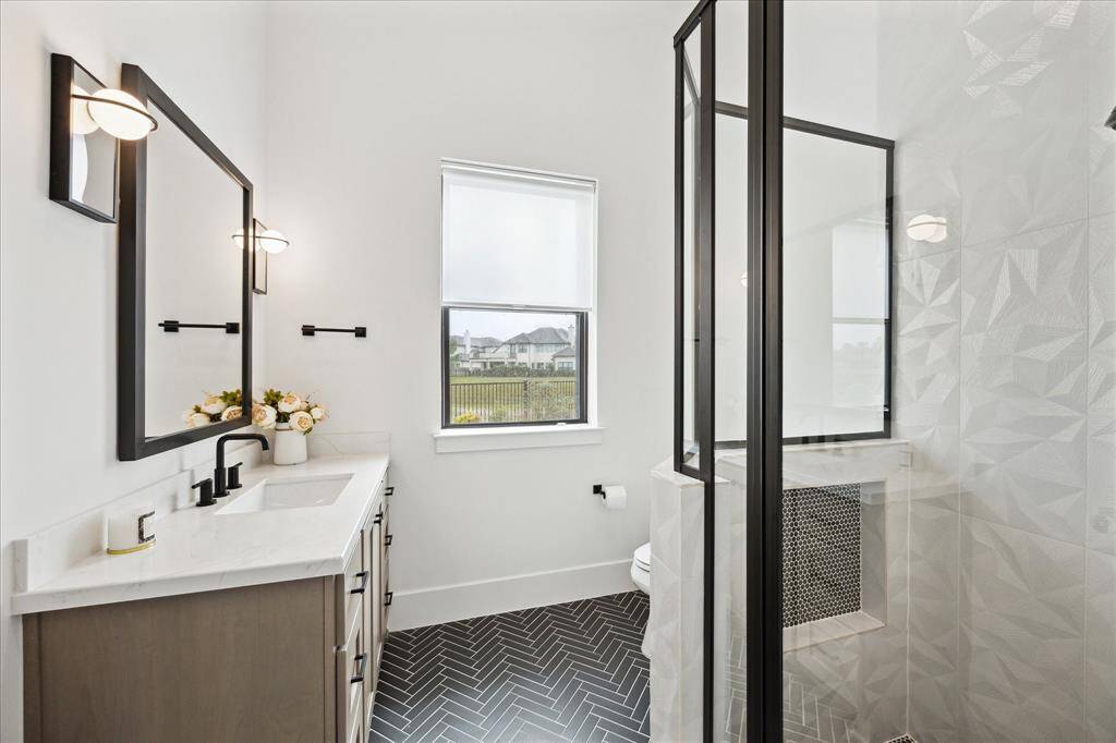 The 1st floor ensuite bath features a walk-in shower with decorative tile and a full-sized quartz vanity.
