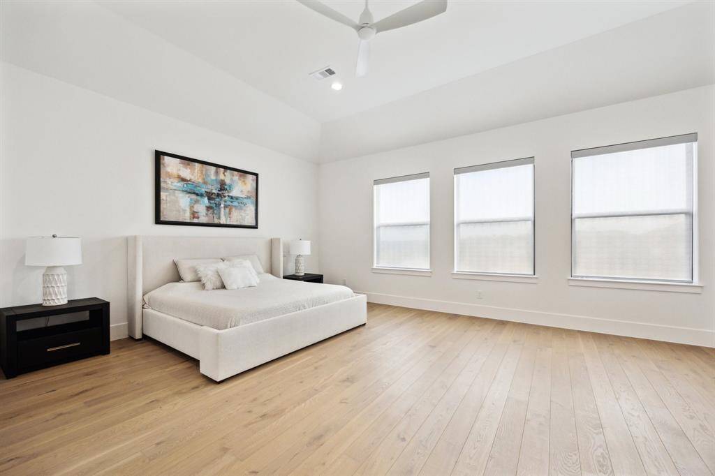 The primary bedroom, overlooking the lake, is complemented by a ceiling fan, automatic blinds, and hardwood floors. It also boasts an impressive walk-in closet and a luxurious ensuite bath.