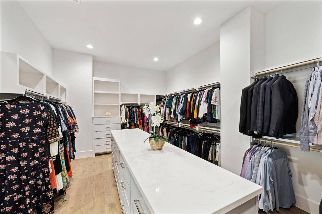 Sliding double doors lead to a dramatic walk-in closet with a central island for storage, complemented by custom built-ins for optimal organization.