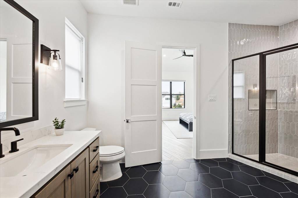 The secondary bath features granite countertops, striking geometric tile, a walk-in shower, and a spacious walk-in closet with a laundry shoot. There is also a storage closet off the walk in closet.