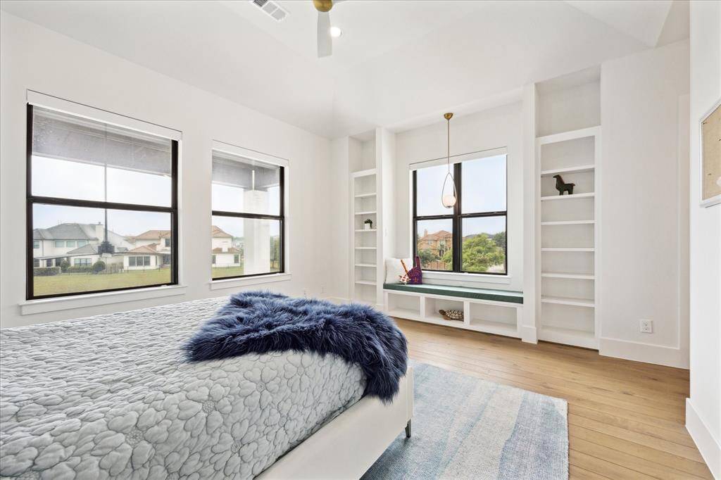 This secondary bedroom includes a charming seating area, custom built-ins, and an exceptionally large walk-in closet, also outfitted with built-in storage.