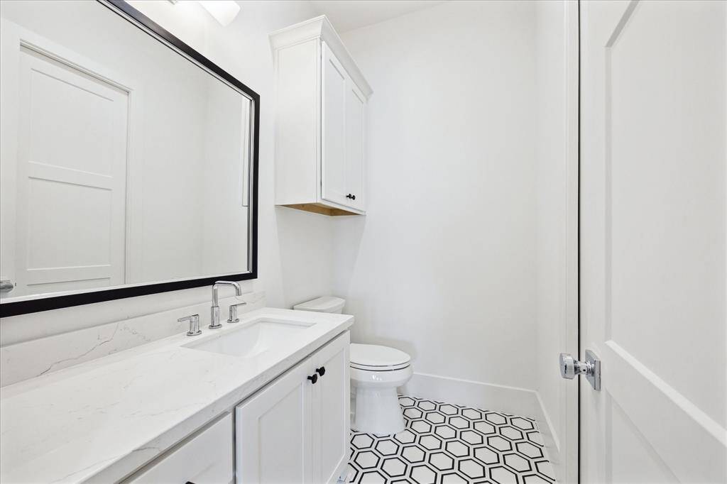 The second-floor powder bath showcases designer tile, stylish lighting, and elegant quartz countertops. It is direclty accessible from the gym.