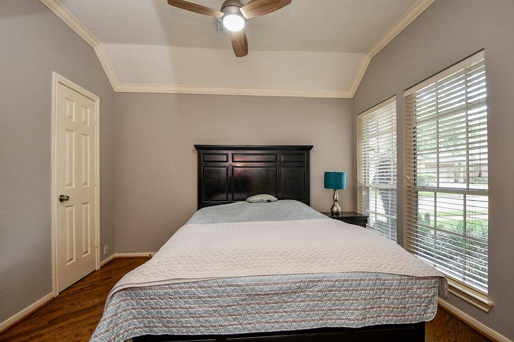 Guest bedroom with wood floors and crown moulding.