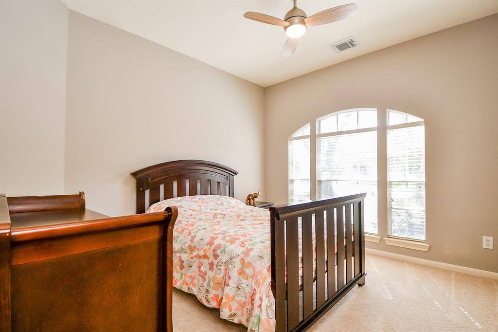 Second guest bedroom with high ceiling, ceiling fan and windows allowing for sunlight.