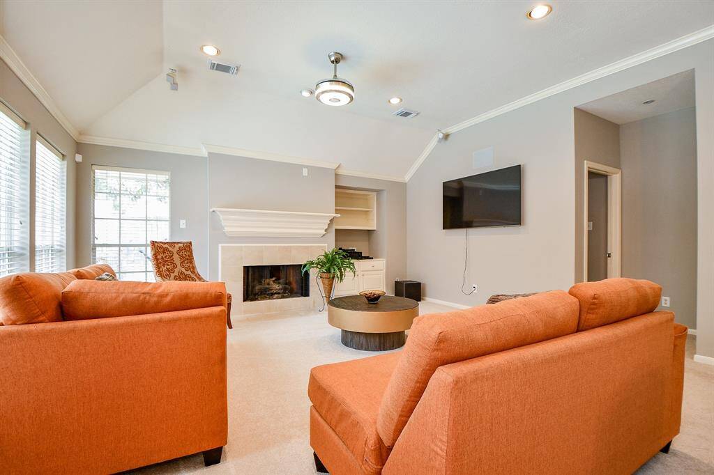 Family room open for entertaining and gathrings, with a ceiling fam and windows for ample sunlight to enter into the room.