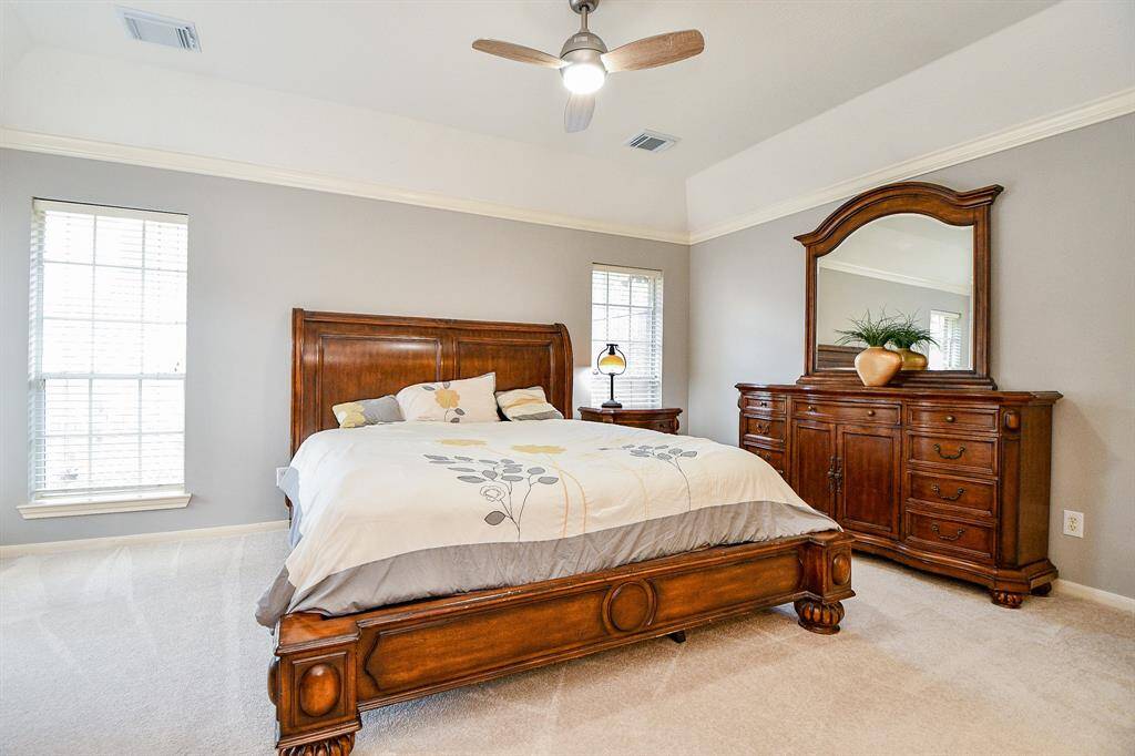 Primary bedroom with ceiling fans and high ceilings.