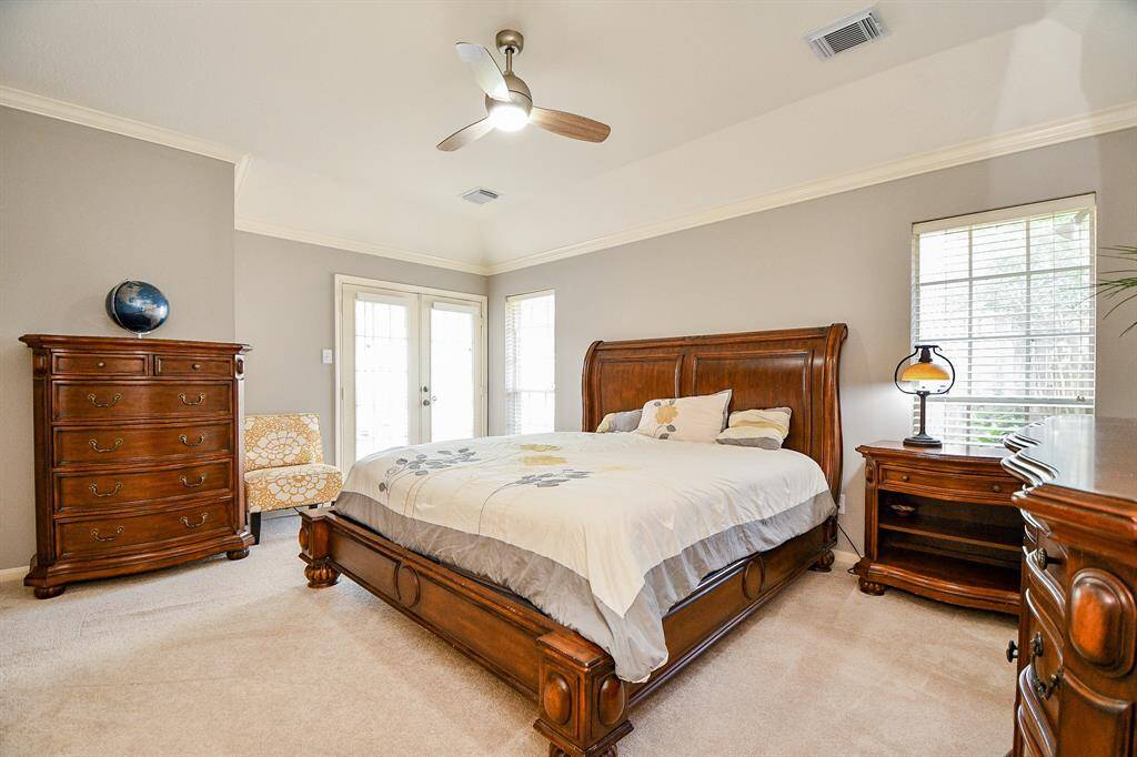 Primary bedroom view of windows and  double doors allowing acess to backyard/pool/spa.