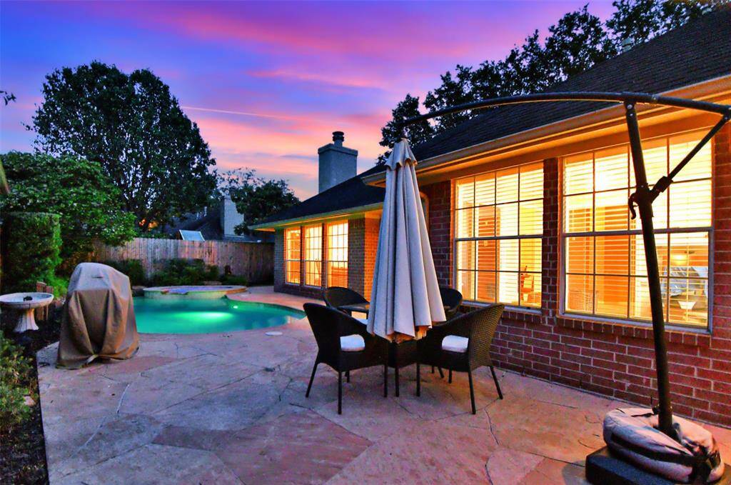 Twilight view of pool and lush landscaping.
