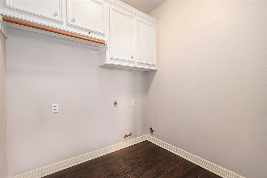 Laundry room has built-in shelves and is next to the kitchen.