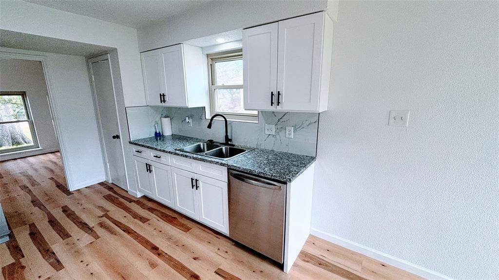 Bright kitchen area featuring modern white cabinets, granite countertops, and a stainless steel sink.