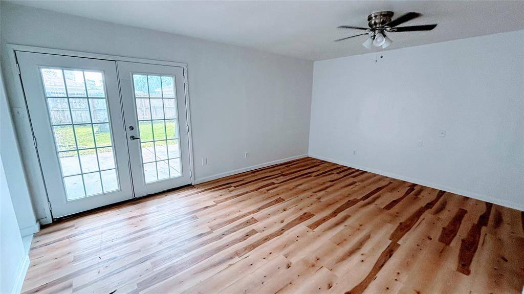 Bright and spacious bedroom 2 featuring  double French doors leading to the fenced backyard.