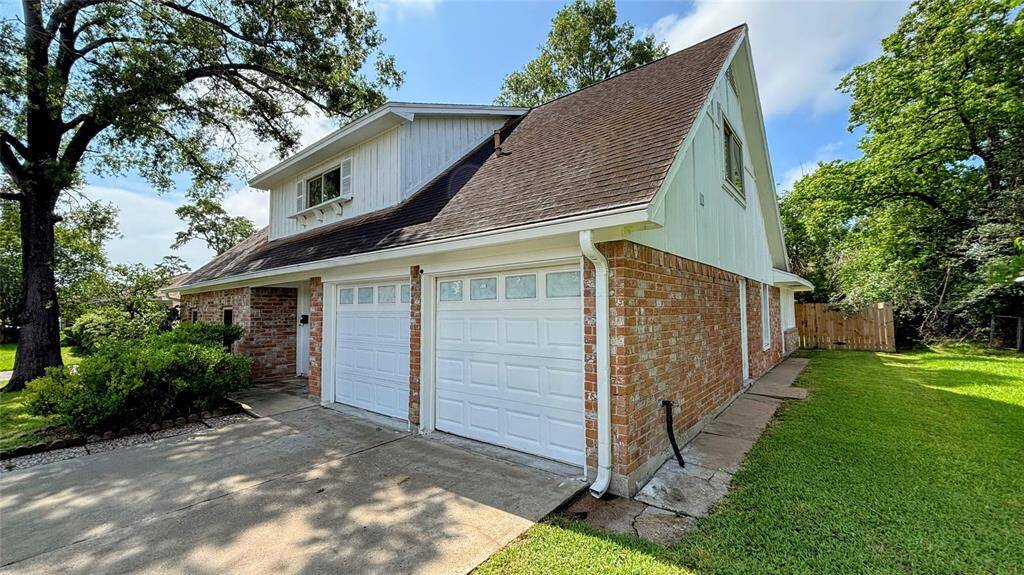 This charming two-story home includes a spacious driveway leading to a double garage. The property is surrounded by mature trees and well-maintained greenery.