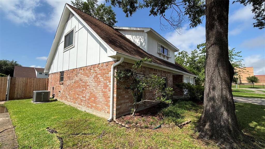 Another view of the property surrounded by a well-maintained lawn and mature trees.
