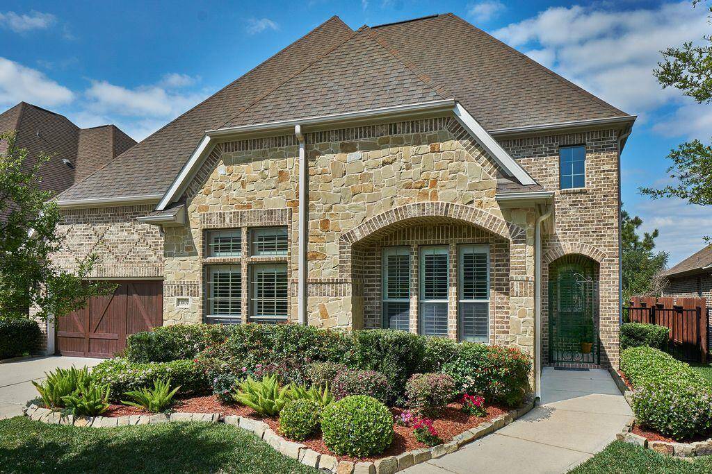 Recent Construction in a gated community boasts a stone and brick exterior and manicured landscape.