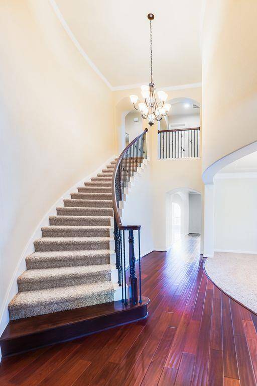Sweeping staircase with wrought iron hand rails. Hand scraped cherry wood floors flow through the entry into the living room.