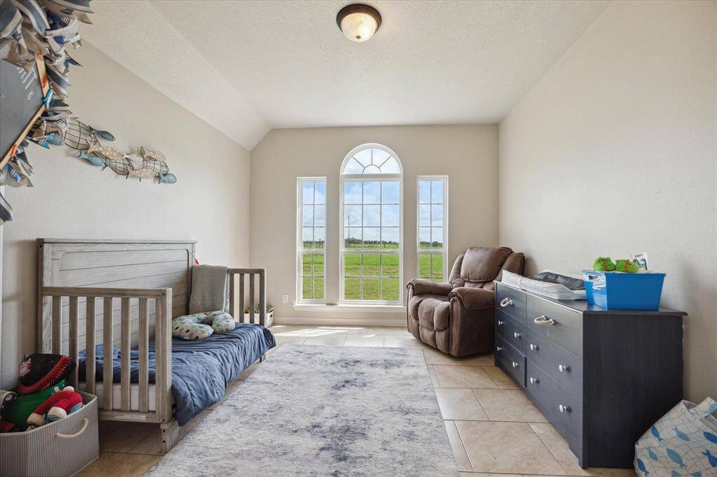 You're looking at a bright, spacious STUDY / HOME OFFICE featuring a large arched window that lets in plenty of natural light, showcasing a view of the open outdoors. The room is currently used as a 5th bedroom.