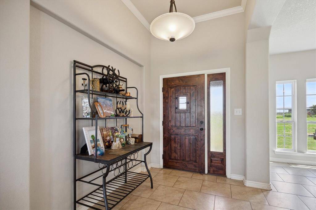 This is a welcoming entryway featuring a sturdy wood front door with glass panels, tiled flooring, and neutral wall colors. There's ample natural light from the side window.
