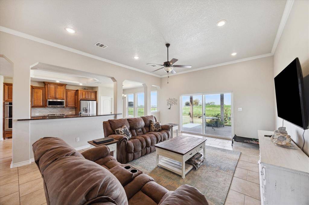 Spacious living area, open-concept kitchen with wooden cabinetry, and ample natural light. Glass door leads to an outdoor view.
