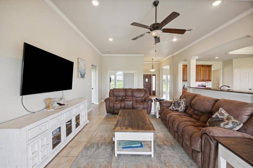 This is a spacious and inviting living room with high ceilings, and an open floor plan that connects to the kitchen area. The room is well-lit with a combination of natural and ceiling light.