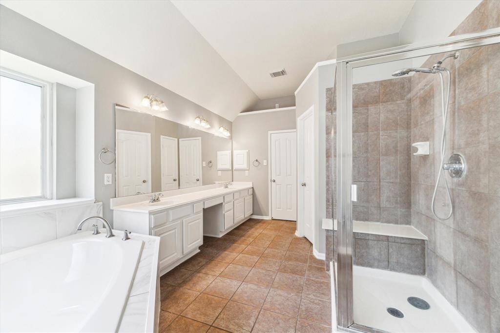 ELEGANT GLASS-ENCLOSED WALK-IN SHOWER AND DUAL SINKS WITH A VANITY AREA.