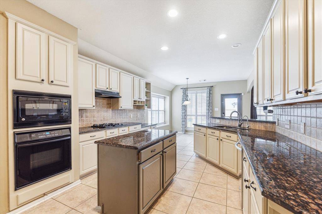 BEAUTIFULLY UPDATED KITCHEN WITH GLEAMING GRANITE COUNTERS AND A GAS COOKTOP, IDEAL FOR THE HOME CHEF.