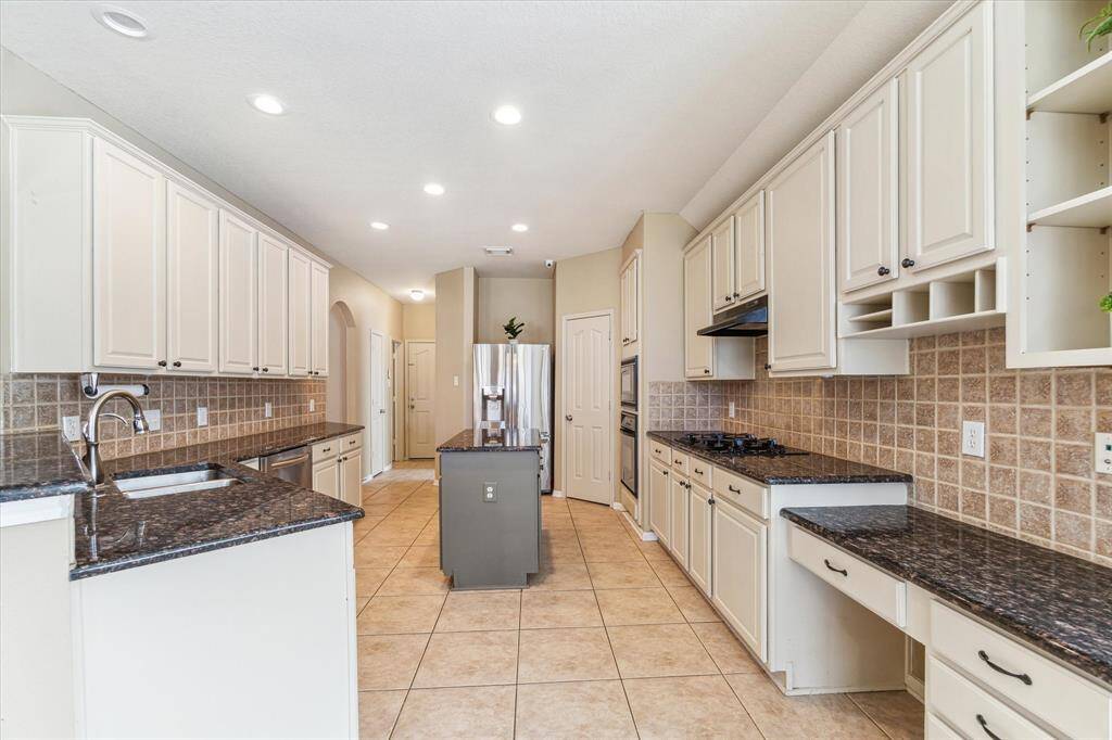 SPACIOUS KITCHEN FEATURING ELEGANT CABINETS AND BLACK APPLIANCES, INCLUDING A BUILT-IN MICROWAVE AND DISHWASHER.