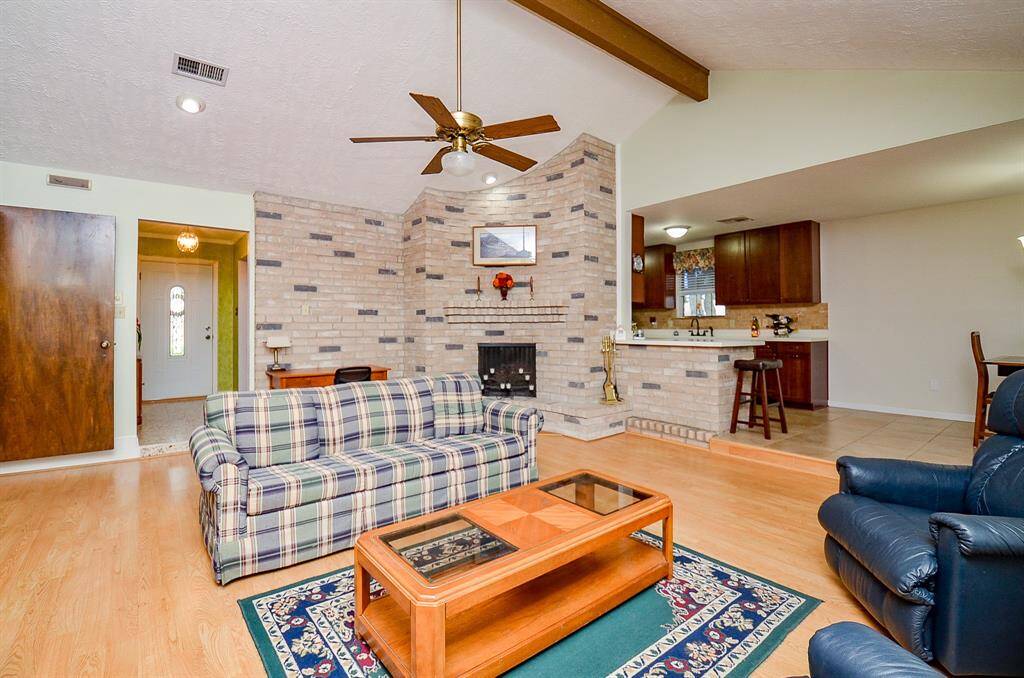 The living area features high ceilings with a wooden beam and a curved fireplace.