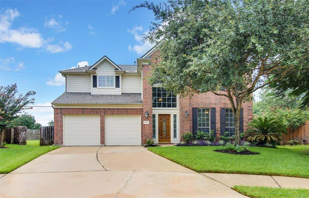 This charming two-story brick home features a double garage, large front windows, and a welcoming wooden door. Surrounded by well-maintained landscaping and mature trees, it offers an inviting curb appeal in a peaceful neighborhood setting.