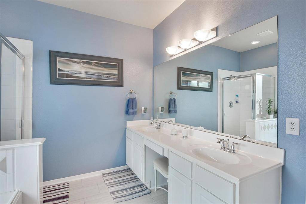 Experience the elegance of the master bathroom, featuring dual sinks with sleek stainless steel faucets and stunning light fixtures.