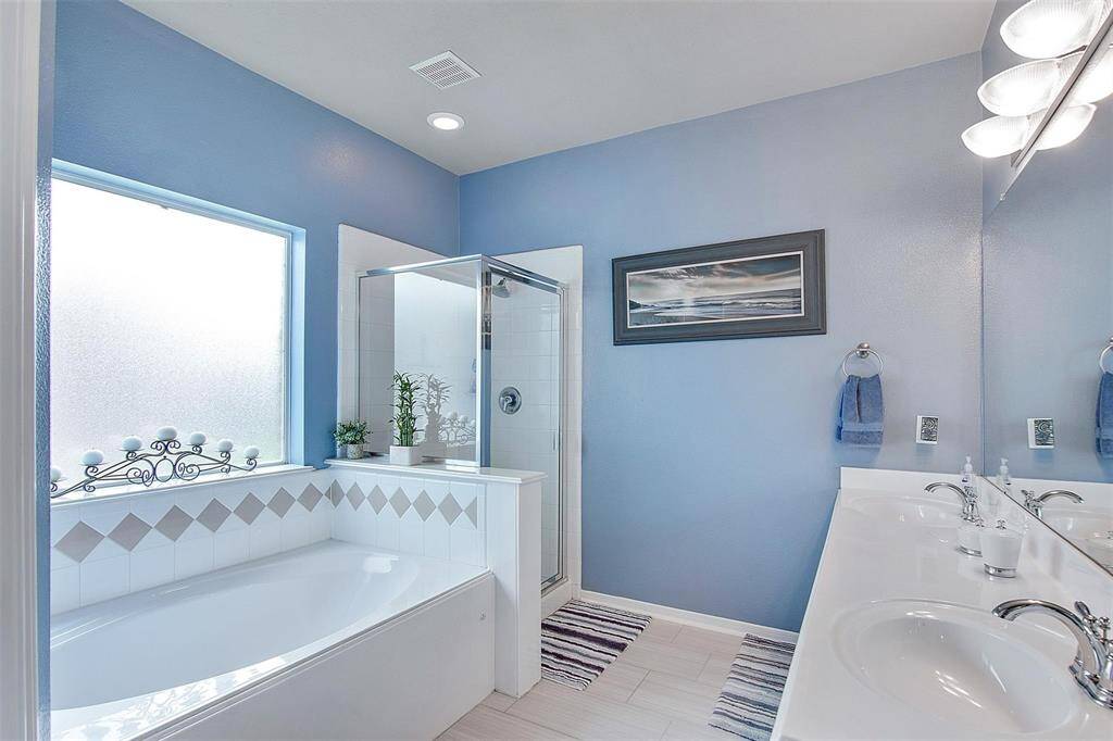 Elegant master bathroom featuring dual sinks, a separate tub, and shower with sleek stainless steel fixtures.
