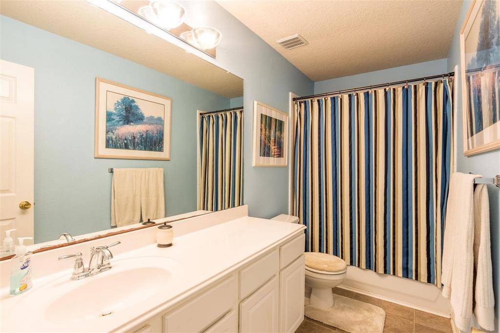This secondary bathroom features a clean, modern design with a long vanity.
