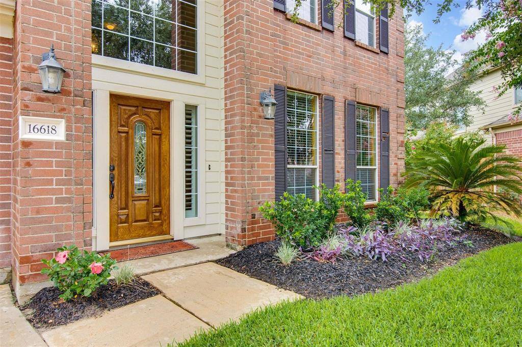 Beautiful elevation with tall windows for lots of light. The well-maintained landscaping includes lush greenery and colorful flowers, enhancing the inviting curb appeal.