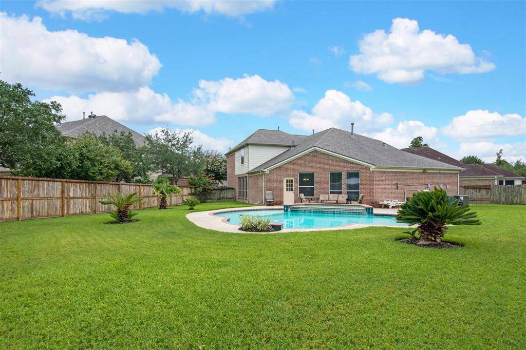 Welcome to your backyard oasis featuring a pristine in-ground pool and lush landscaping.
