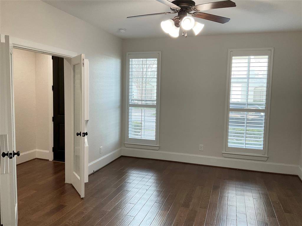1st floor room right off the entry room with hardwood floors, featuring two large windows with shutters and a ceiling fan. It has double doors leading to your front entry, creating an open and airy feel.