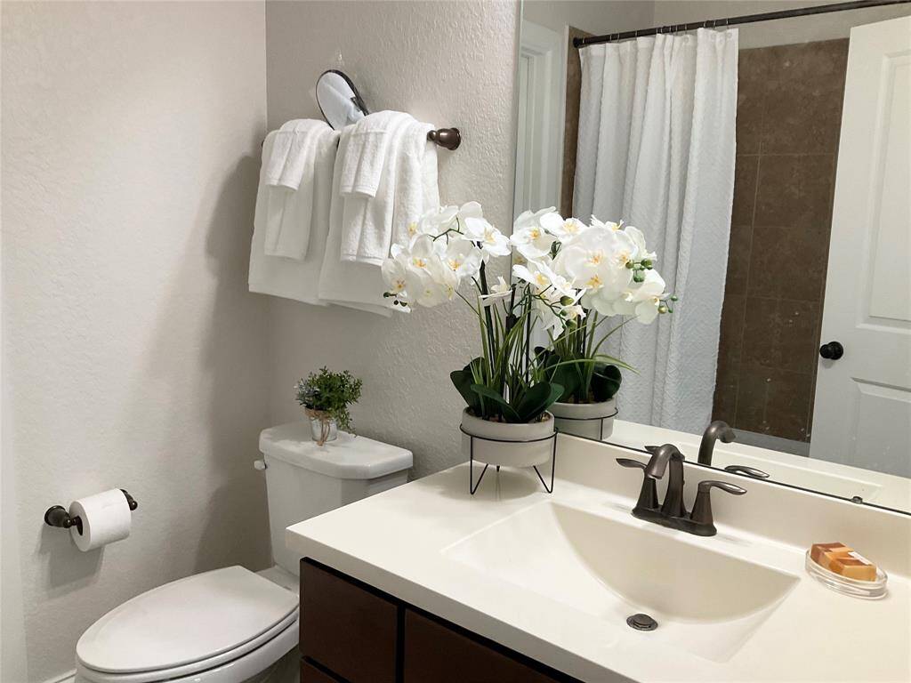 A modern bathroom with a clean design, featuring a white countertop with a sleek faucet. The  guest bathroom offers a tub/shower combination and neutral wall tones for a fresh, inviting atmosphere.