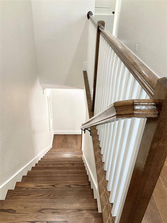A beautiful staircase with polished wooden steps and a sturdy handrail, leading down to a bright, light hallway which is your front door entrance. The staircase creates a clean and inviting transition between floors.  You have an elevator if your have already hit your 10,000 steps today.