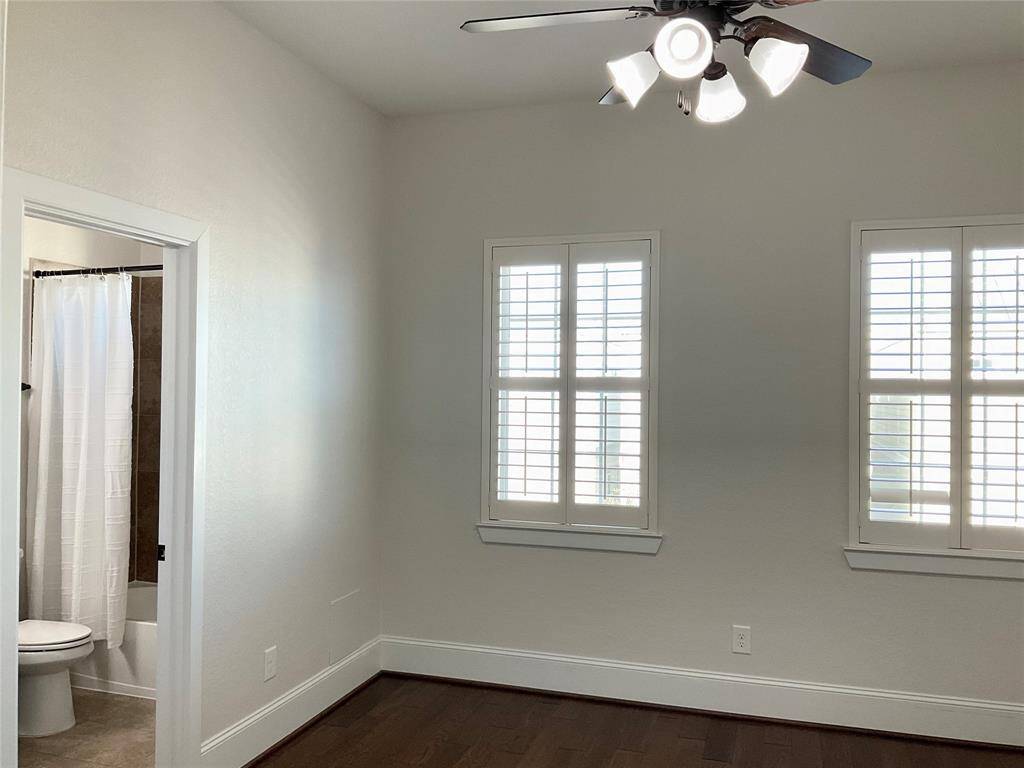 The secondary bed room features hardwood floors, ample natural light from two windows with shutters, a ceiling fan with lights, and an adjacent bathroom with a shower and tub combination.  The bedrooms are at separate ends of the hall offering space but not to far away.