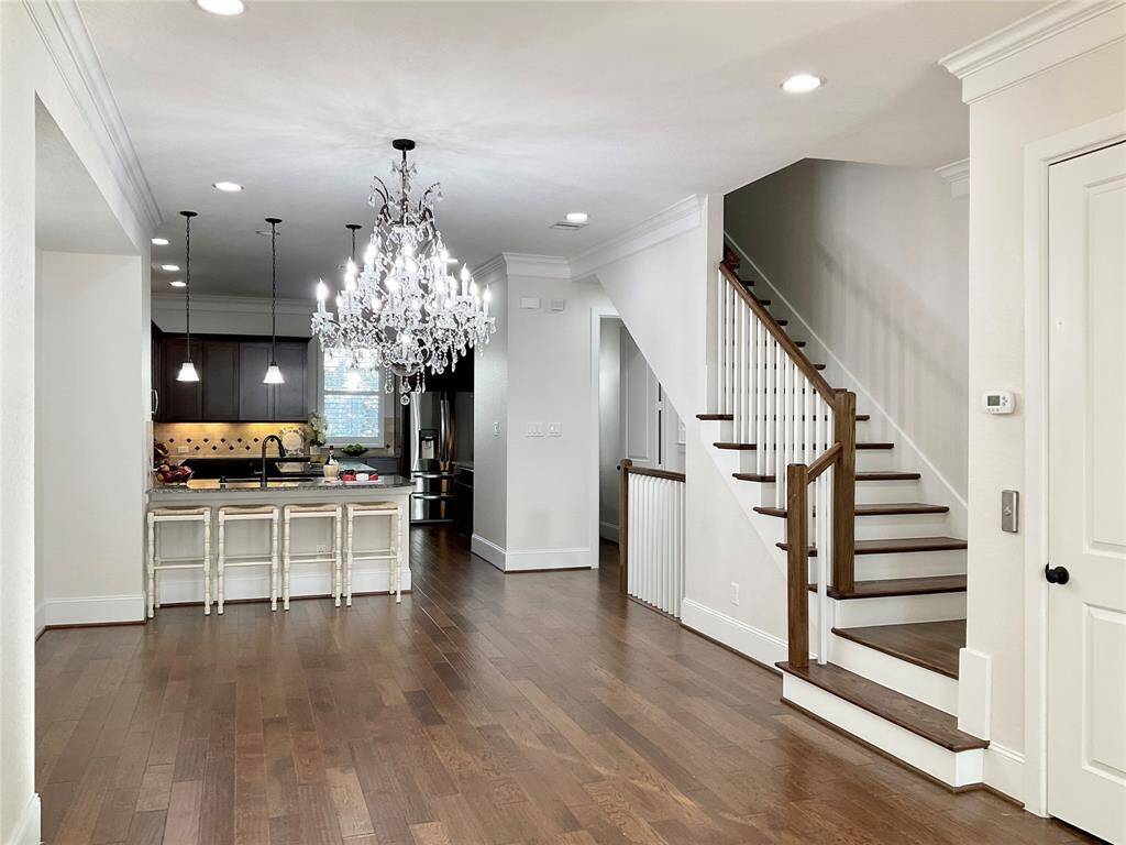 This elegant home features an open floor plan with hardwood floors, a large kitchen, stainless appliances, under counter lighting and an island with granite countertops, a stunning chandelier, and a stylish staircase. Perfect for entertaining and comfortable living.