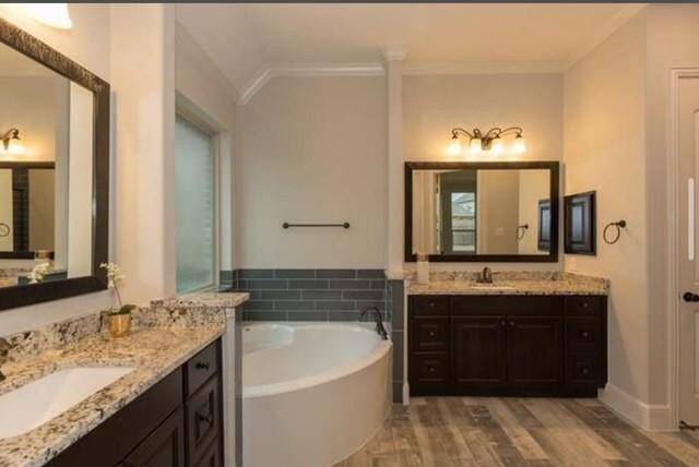 This bathroom features a luxurious design with granite countertops, a large soaking tub, dual sinks with dark wood cabinetry, and stylish lighting fixtures. The neutral tones and tile flooring create a warm and inviting atmosphere.