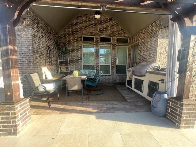 Stylish and spacious covered patio featuring rich brickwork, vaulted ceilings, and a ceiling fan for year-round comfort. This outdoor living area is ideal for entertaining.