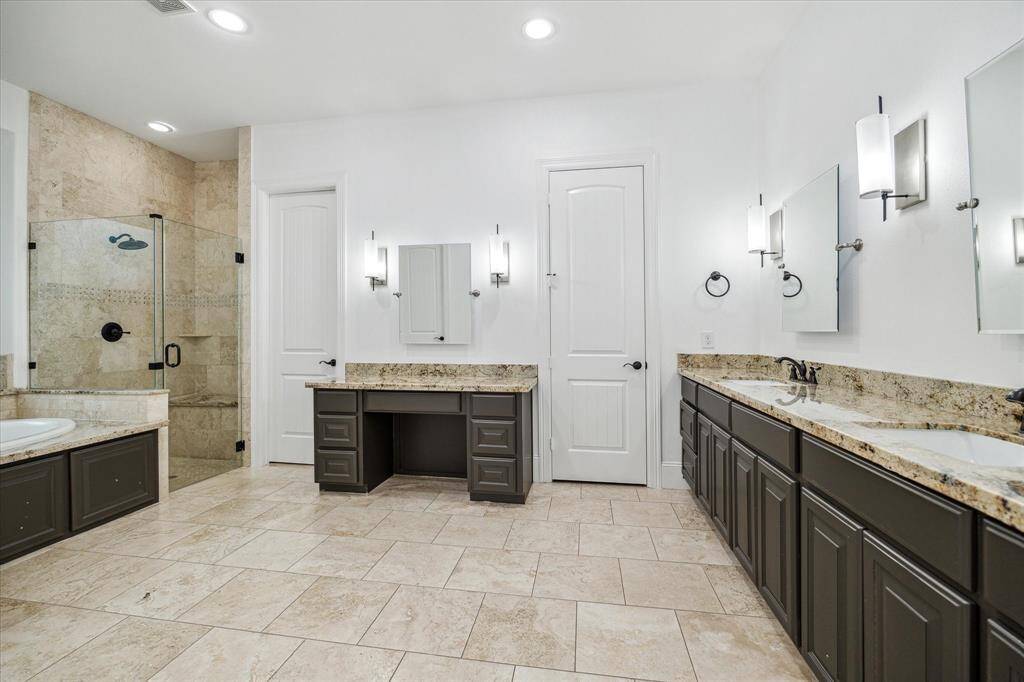 Well appointed primary bathroom with dual sinks an a separate make-up vanity. Doors lead to private lavatory closet and two walk-in closets.