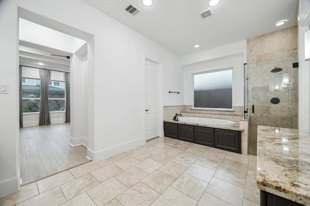 Well appointed primary bathroom with dual sinks an a separate make-up vanity. Doors lead to private lavatory closet and two walk-in closets.