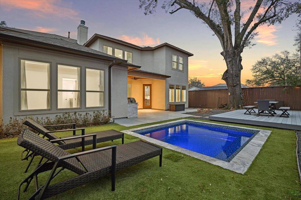 This modern two-story home features a spacious backyard with a sleek pool, a covered patio, and ample windows for natural light, all set against a beautiful sunset backdrop. Perfect for entertaining and relaxation.