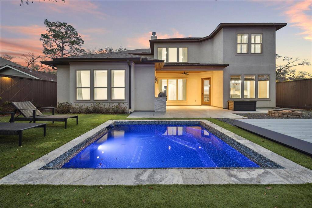 This modern two-story home features a spacious backyard with a sleek pool, a covered patio, and ample windows for natural light, all set against a beautiful sunset backdrop. Perfect for entertaining and relaxation.